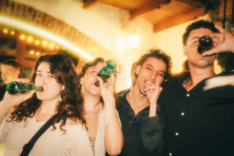 Four people drinking beer and smiling for a photo.